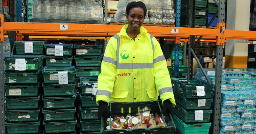 FareShare London volunteer Chisom holds a tray of surplus food saved from waste