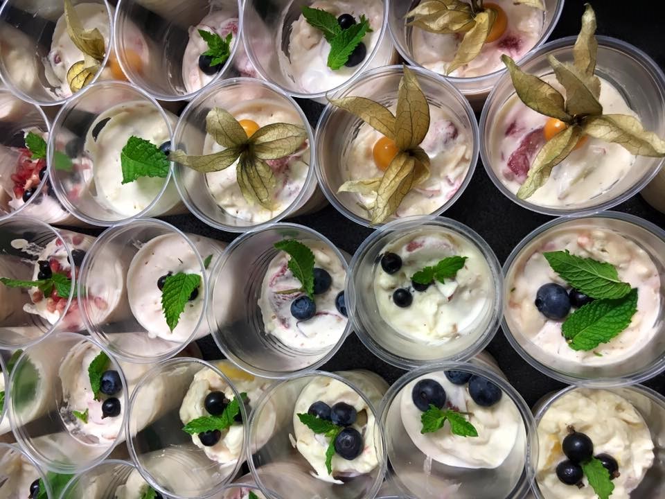 FirstBite's very own version of eton mess, featuring surplus fruit from FareShare. Photo shows many cups of the dessert decorated with mint, sharon fruit and blueberries. 