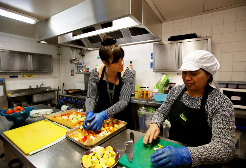 May0080973. The Daily Telegraph. Layla, the catering manager (left) and Fely (right), a service user, are seen preparing food in the kitchen of The Marylebone Project, a women's refuge, in Marylebone, London, which benefits from the charity Fare Share. Excess food from supermarkets is distributed by the charity Fare Share to needy people such as the service users of the Marylebone Project, many of whom are vulnerable and homeless women. Fare Share is the UK's largest charity fighting hunger and food waste, and is one of this year's Telegraph Christmas Charity Appeal chosen charities. Tuesday January 16, 2018.