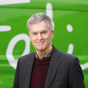 Headshot of Justin Byam Shaw smiling at camera standing in front of green van with Felix signature